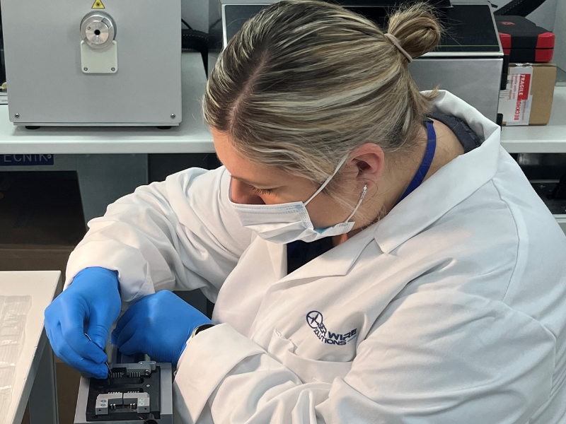 Person handling micro fine wires in lab on a laser wire stripping fixture plate